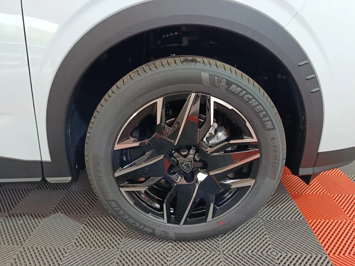 Gros plan sur la roue avant droite blanche du Peugeot 3008 1.2 HYBRID 145 GT avec jante noire brillante et pneu Michelin.