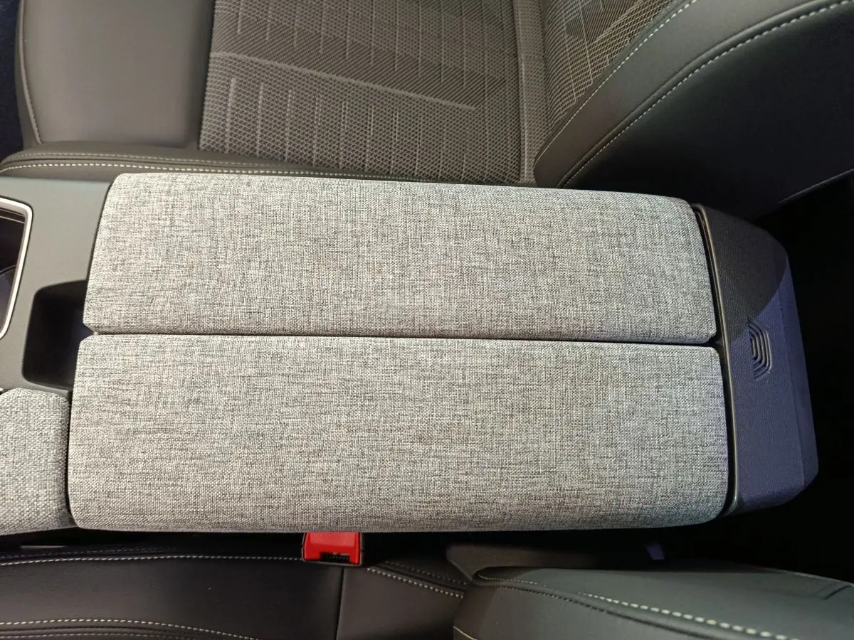 Accoudoir central en tissu gris clair vu de dessus dans l'habitacle du Peugeot 3008 1.2 HYBRID 145 GT blanc.