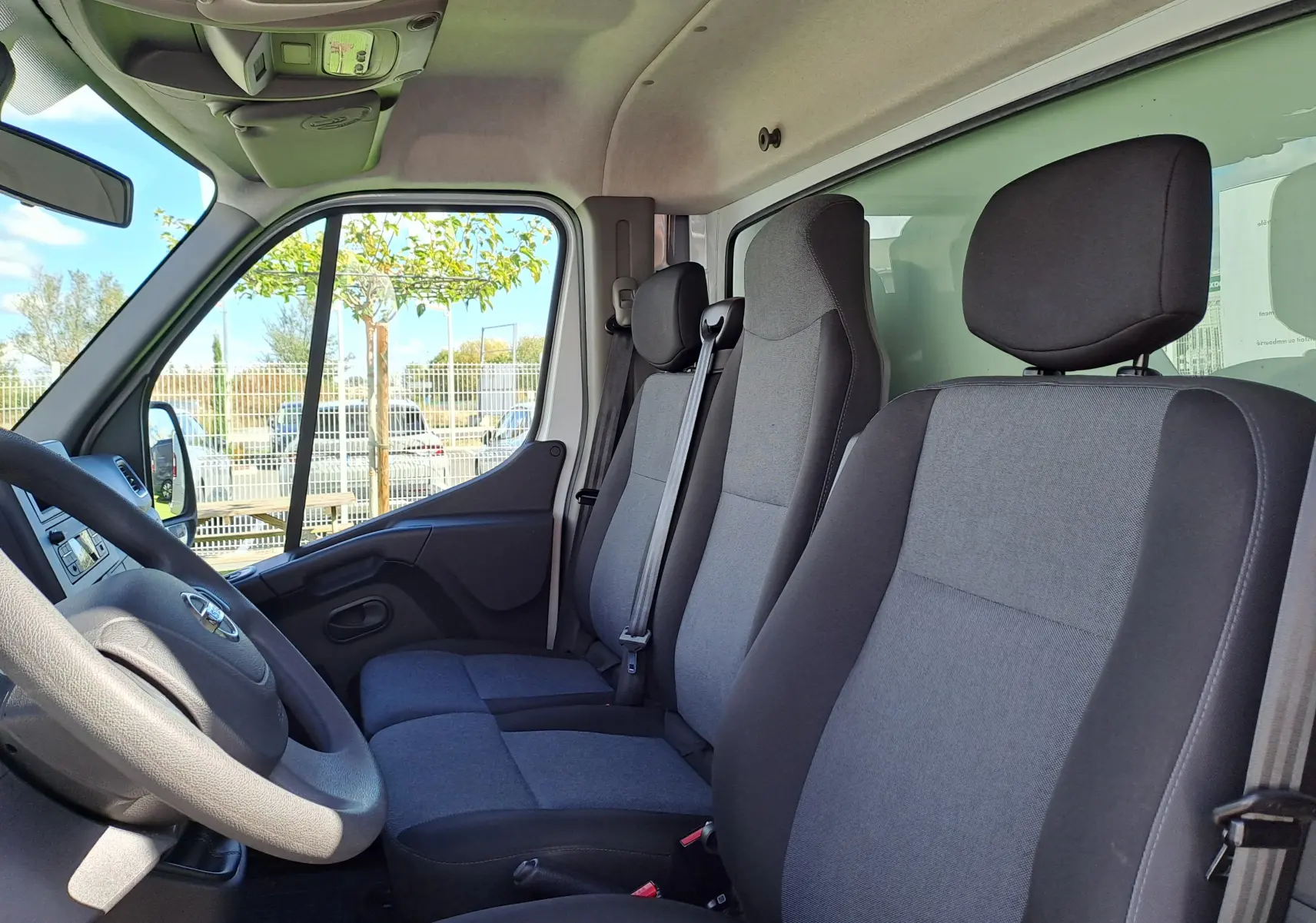Vue intérieure côté conducteur du Nissan Interstar Chassis Cabine blanc 2024, montrant les sièges gris et tableau de bord.