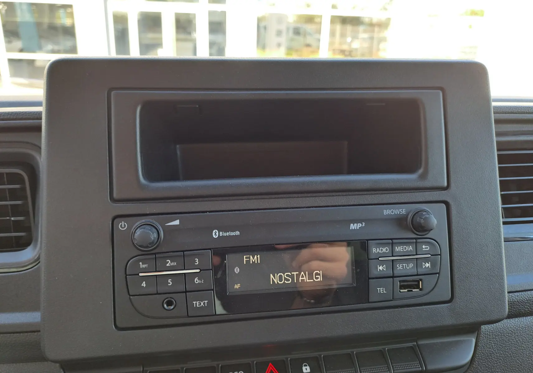 Vue rapprochée de la radio Bluetooth du tableau de bord du Nissan Interstar blanc, version 2024, avec écran FM affichant "NOSTALGI".