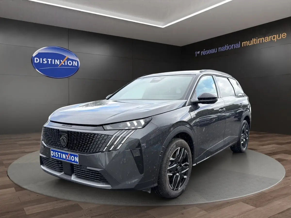 Peugeot 5008 gris foncé en 3/4 avant droit, avec calandre noire et jantes alliage noires brillantes.