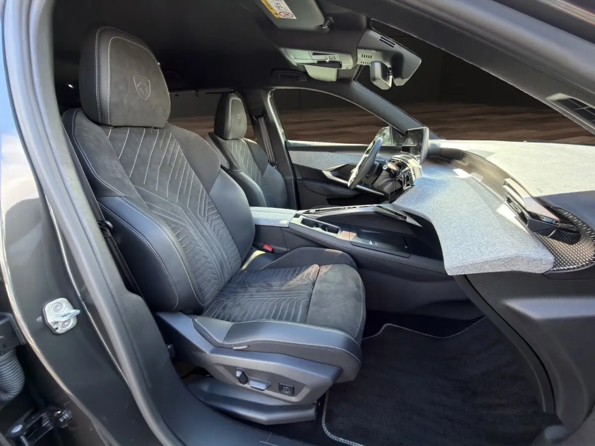 Vue intérieure côté conducteur du Peugeot 5008 gris foncé 2025, sièges Alcantara noirs avec logo Peugeot brodé.