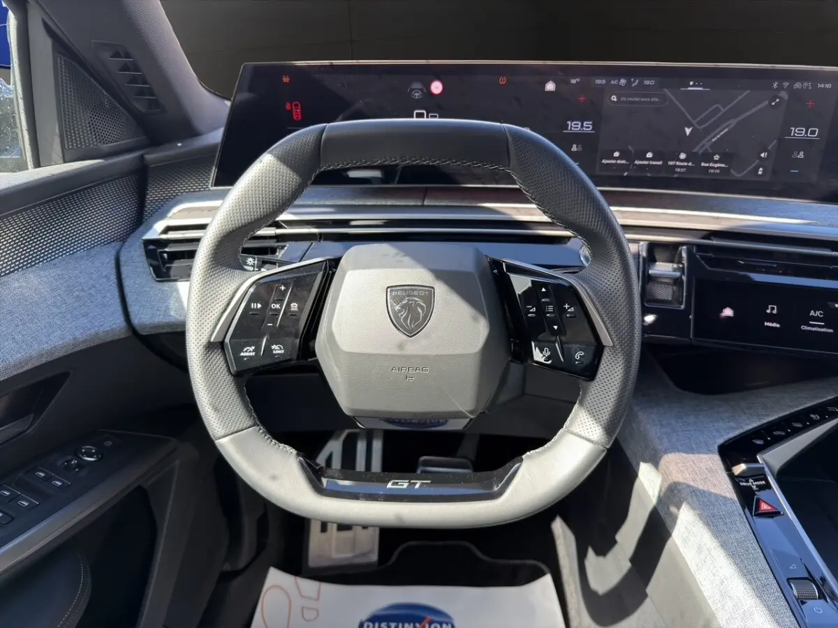 Vue rapprochée du volant cuir GT et du tableau de bord numérique du Peugeot 5008 gris foncé hybride 2025.