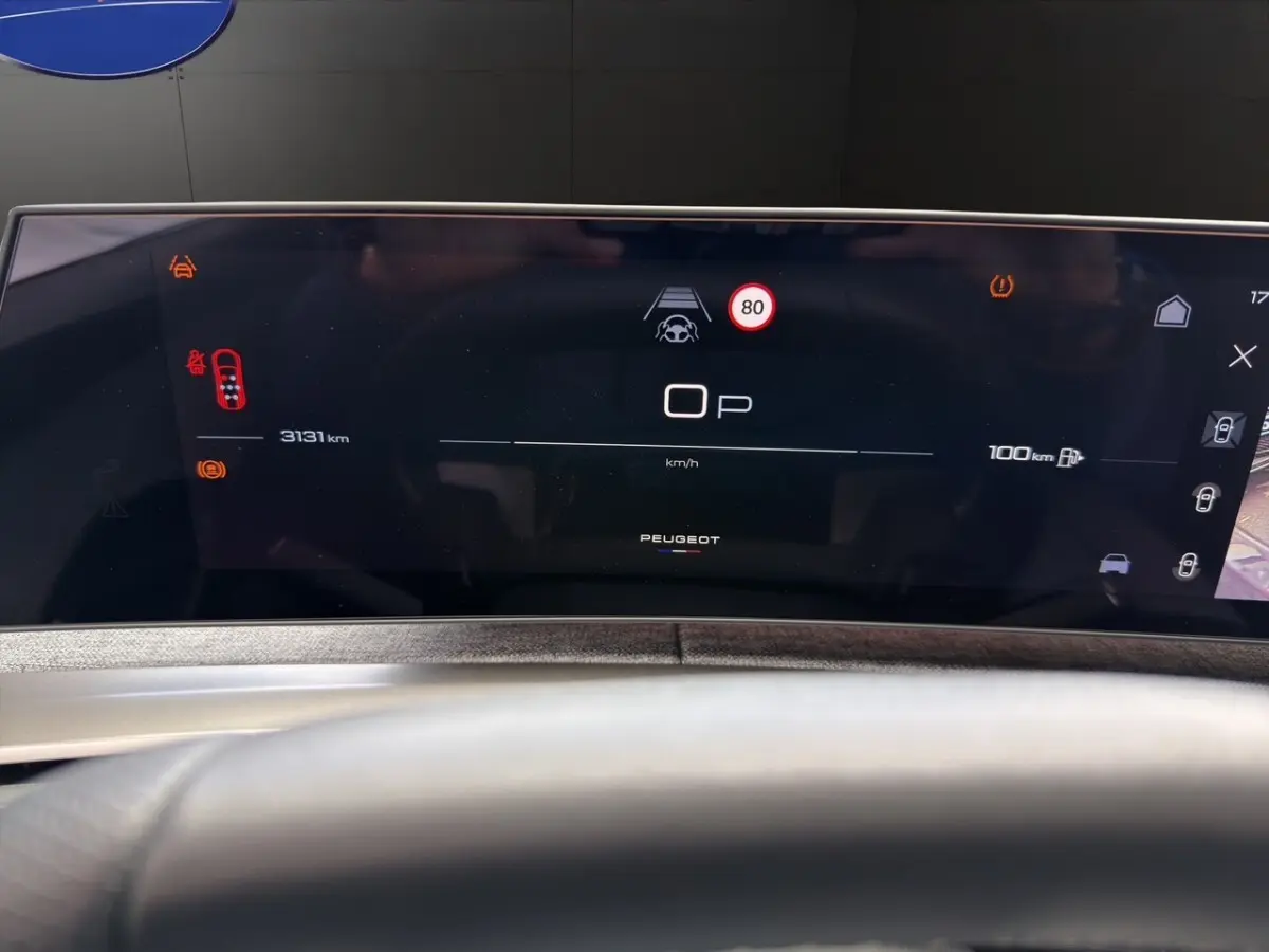 Affichage numérique du tableau de bord du Peugeot 5008 hybride, avec vitesse, alertes et autonomie visible.