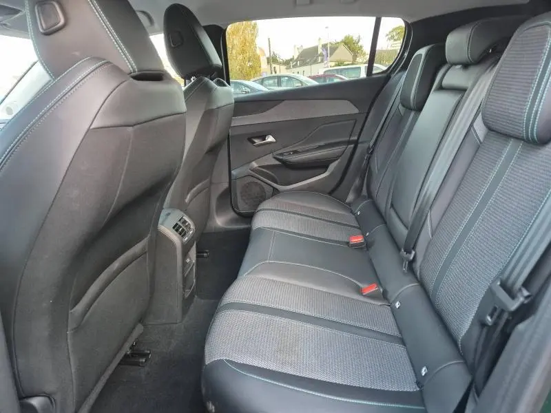 Vue latérale droite de l'habitacle arrière de la Peugeot 308 2023 avec sièges tissu et cuir noir aux surpiqûres bleues.