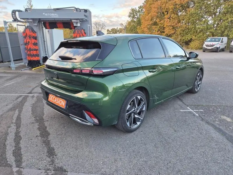 Peugeot 308 vert olivine vue 3/4 arrière droit, feux LED et jantes alliage distinctifs visibles.