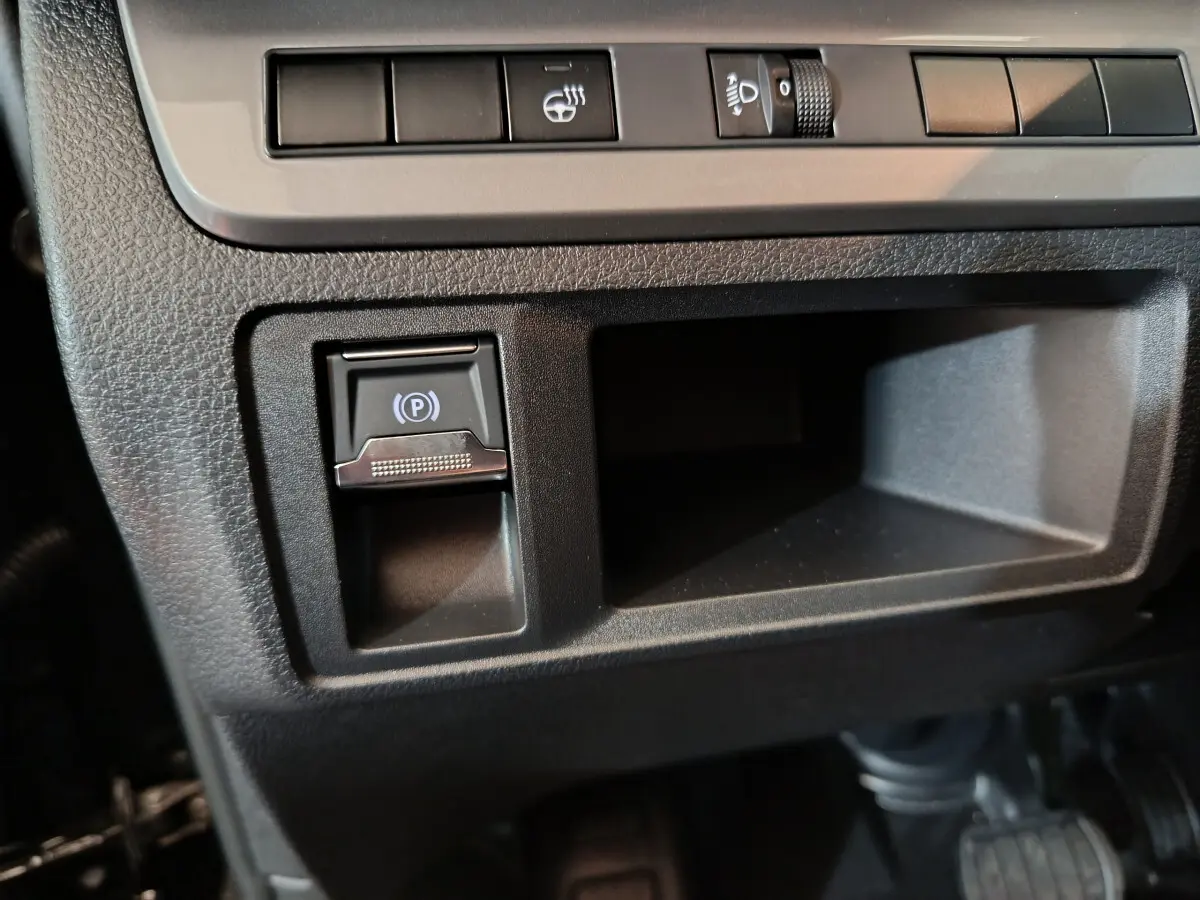 Gros plan sur la console centrale noire du Citroën Jumpy XL 2025, avec bouton de frein à main électrique et commandes d'éclairage.