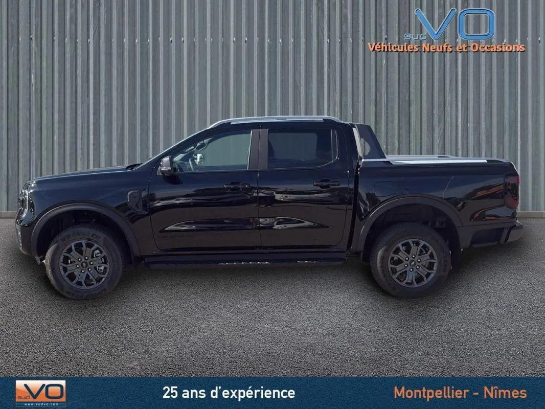 Vue de profil côté gauche du Ford Ranger Wildtrak noir 2025 avec jantes alliage 18 pouces et barres de toit.
