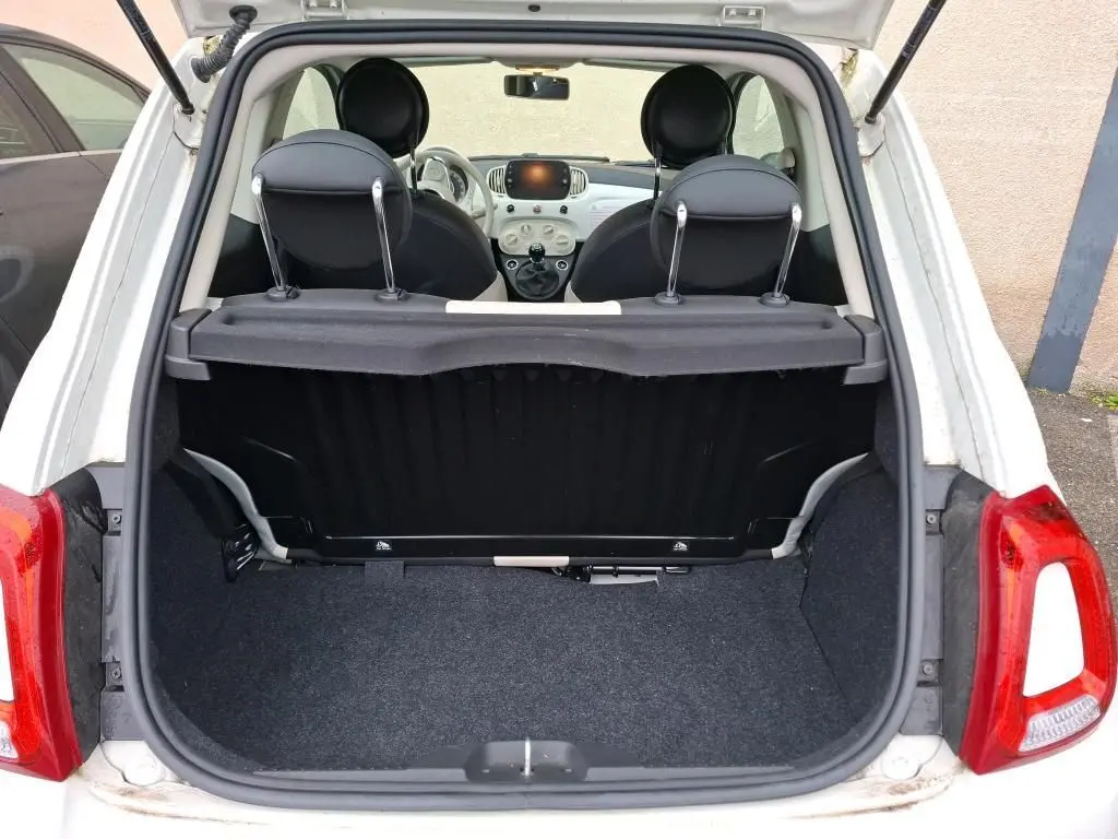 Vue arrière ouverte sur le coffre d'une Fiat 500 blanche Bossa Nova, montrant l'intérieur et le tableau de bord compact.