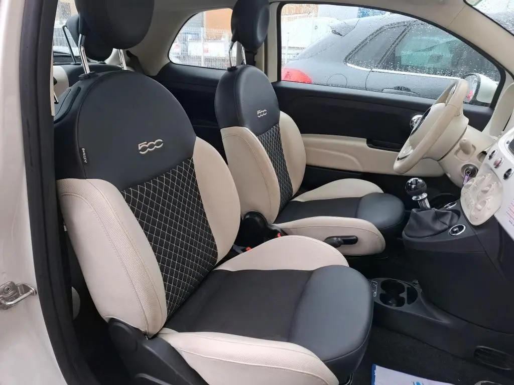 Vue intérieure côté conducteur de la FIAT 500 Dolcevita 2022 avec sièges bicolores beige et noir et volant beige.