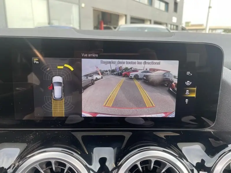 Affichage de la caméra de recul d'une Mercedes GLA 200 D AMG-LINE rouge métal, vue arrière avec lignes de guidage jaunes.