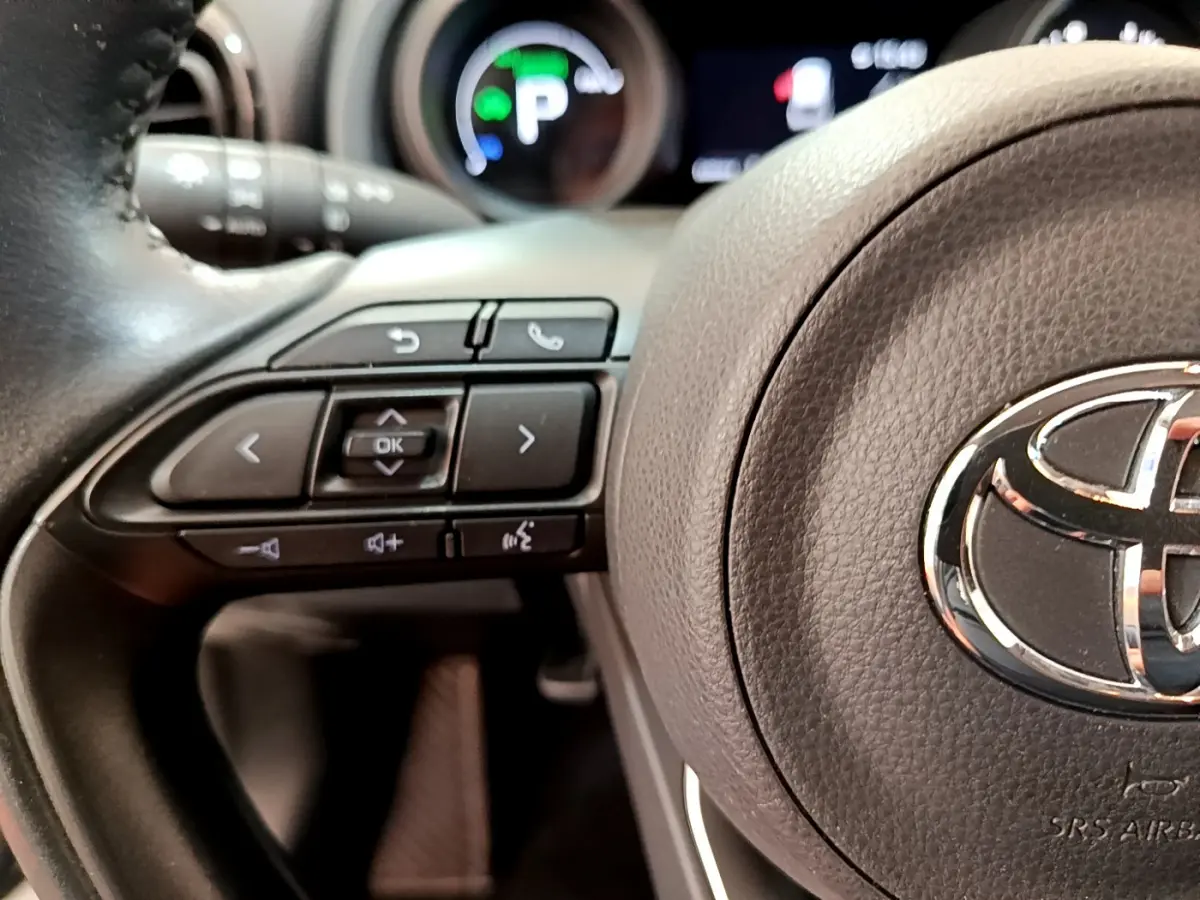 Gros plan sur le volant cuir noir de la Toyota Yaris Cross 2022 avec commandes multifonctions et logo Toyota central.
