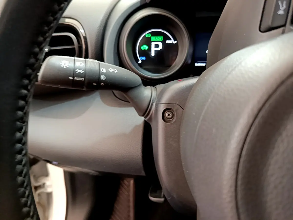 Gros plan sur le combiné d'instruments et le commodo gauche du volant cuir de la Toyota Yaris Cross blanche 2022.