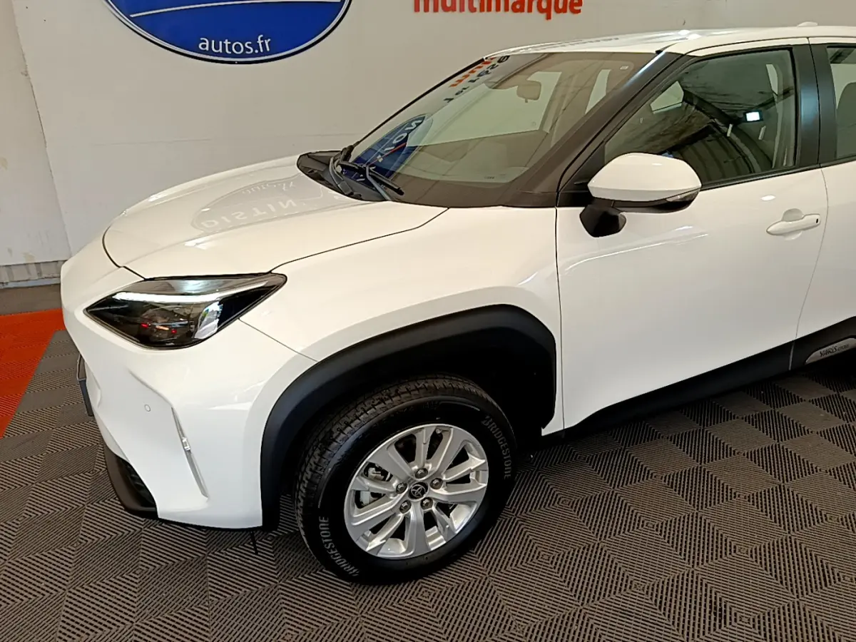 Vue 3/4 avant droit d'une Toyota Yaris Cross blanche avec protections noires autour des passages de roues.
