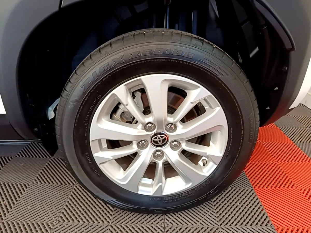 Gros plan sur la roue avant droite du Toyota Yaris Cross blanc, mettant en valeur la jante alliage et le logo Toyota central.