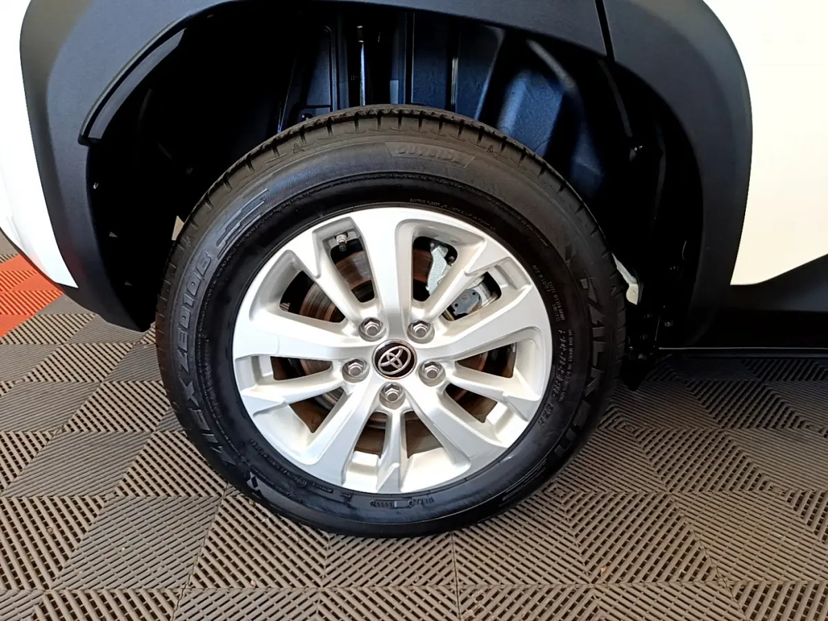 Gros plan sur la roue avant droite blanche d'un Toyota Yaris Cross 1.5 Hybrid 116h avec jante argentée et logo Toyota central.