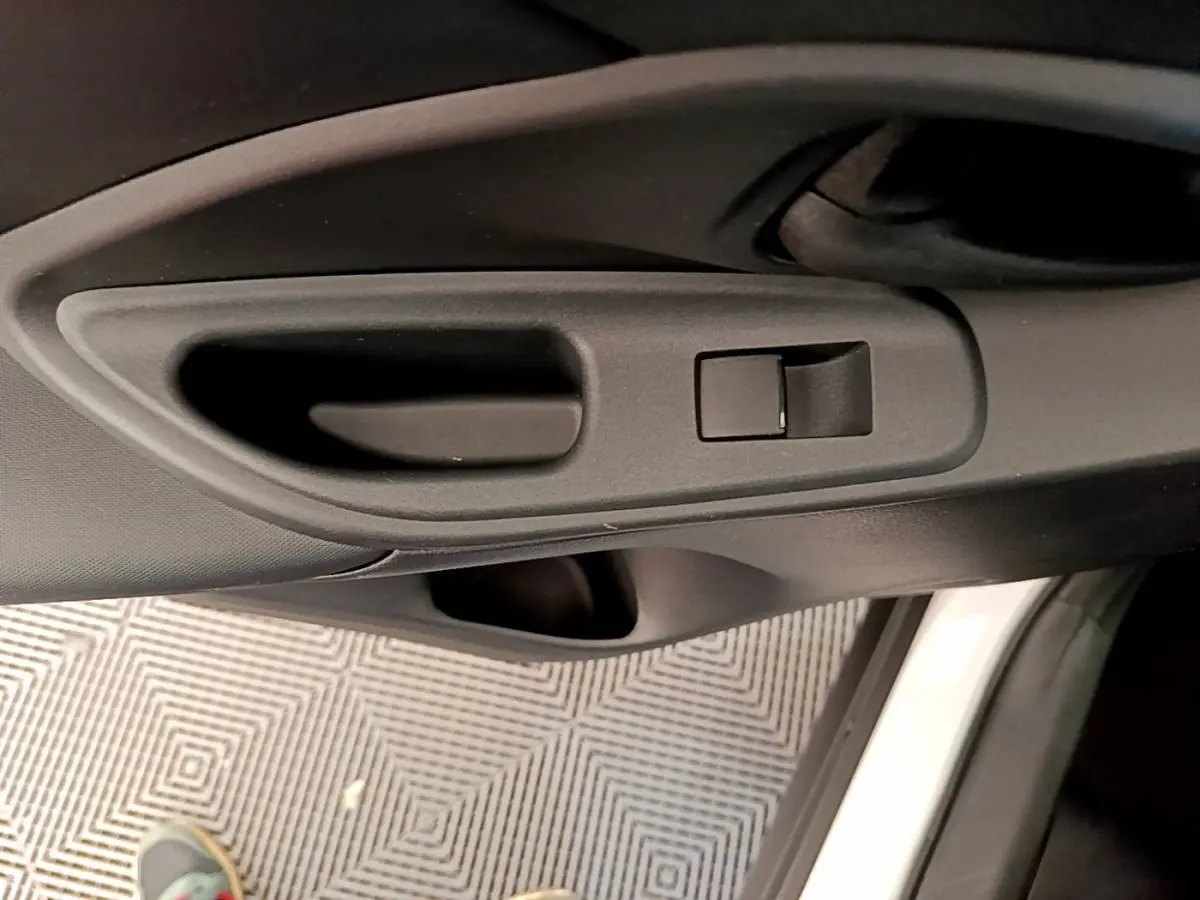 Poignée intérieure noire de la porte côté conducteur d'une Toyota Yaris Cross blanche, vue en gros plan.