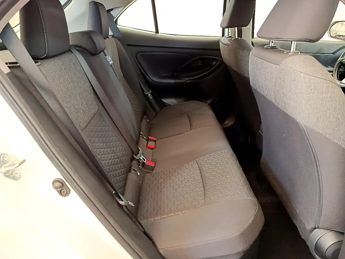 Vue côté gauche de la banquette arrière grise du Toyota Yaris Cross blanc, avec ceintures et appuie-têtes visibles.