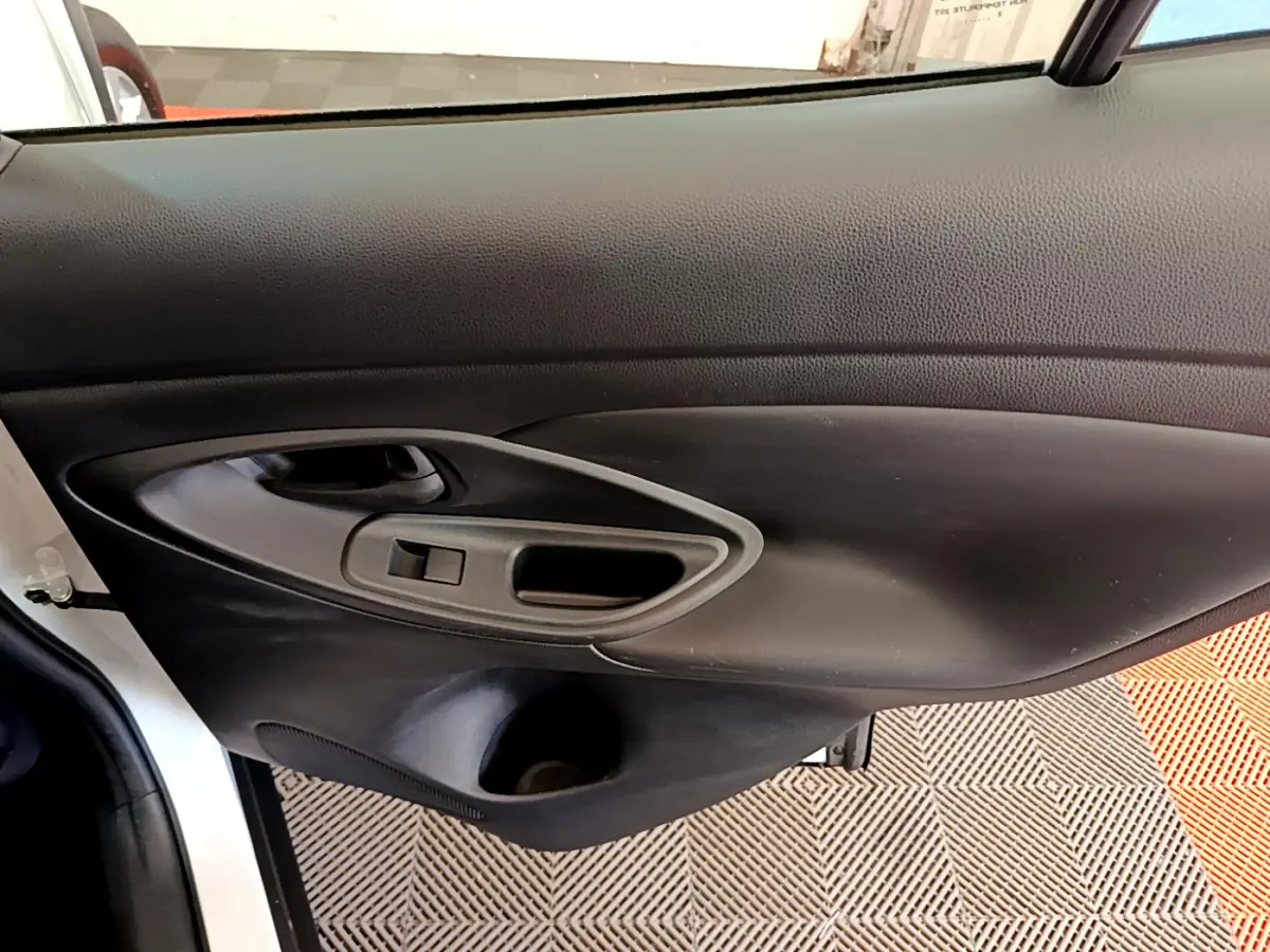 Gros plan sur la porte côté gauche intérieure noire du Toyota Yaris Cross blanc, avec poignée et commande de fenêtre.