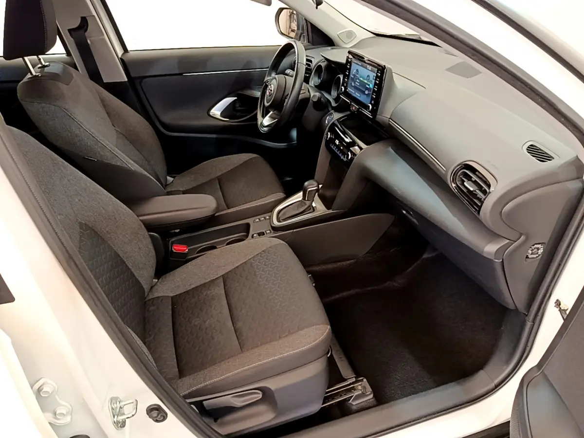 Intérieur avant droit de la Toyota Yaris Cross blanche 2022, avec sièges tissu gris et écran tactile central visible.
