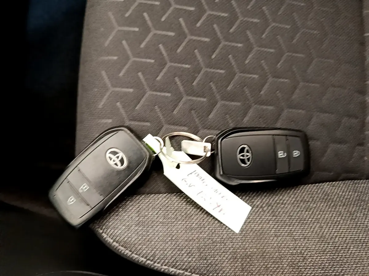 Gros plan sur deux clés Toyota noires posées sur un siège tissu gris à motifs géométriques.