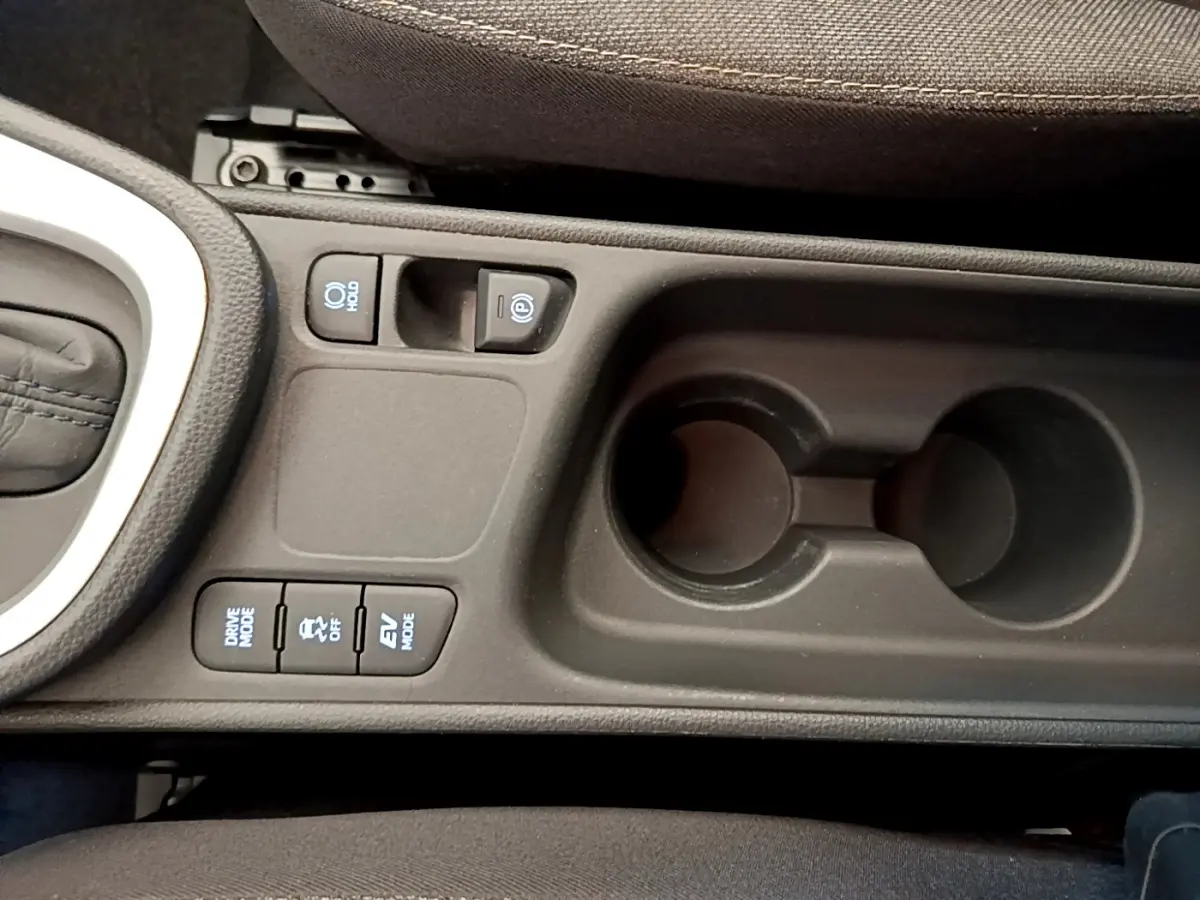 Vue rapprochée de la console centrale noire de la Toyota Yaris Cross 2022 avec boutons de modes de conduite et porte-gobelets.