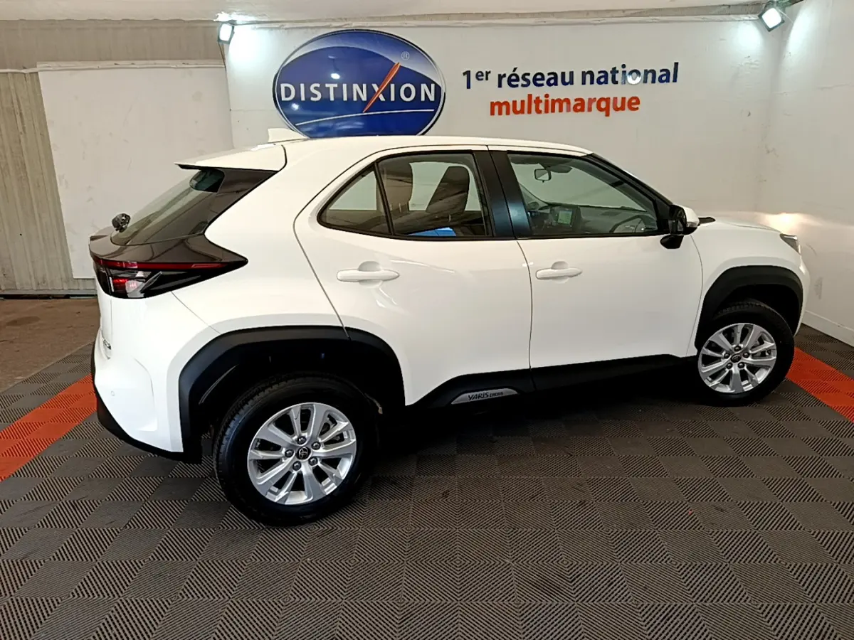 Profil côté gauche d'une Toyota Yaris Cross blanche 2022 en version hybride, dans un showroom lumineux.