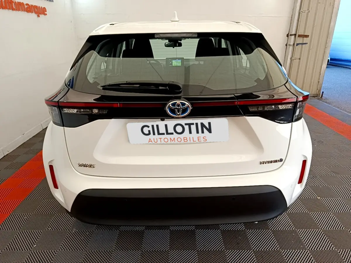 Vue arrière d'une Toyota Yaris Cross blanche avec bandeau noir et logo Toyota centré sur le hayon.