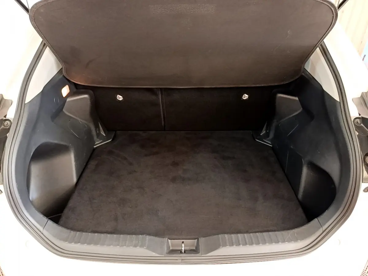 Coffre ouvert vu de face du Toyota Yaris Cross blanc, montrant un espace de chargement propre et spacieux.