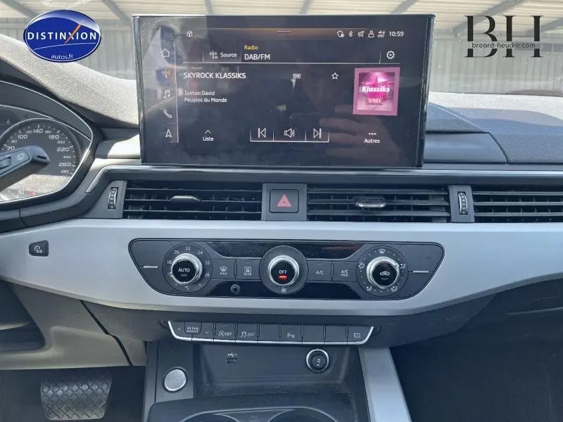 Vue frontale du tableau de bord de l'Audi A4 Avant bleu Navarre, avec écran tactile et commandes de climatisation.