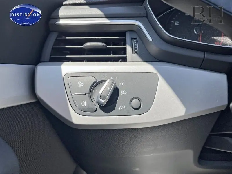 Détail du panneau de commande des phares côté gauche dans l'habitacle d'une Audi A4 Avant bleu Navarre métallisé.