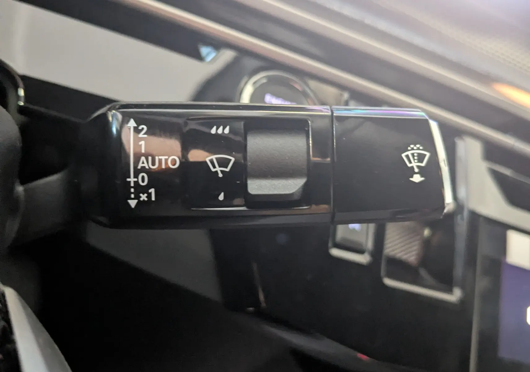 Gros plan sur la commande d’essuie-glace du Peugeot 3008 Hybrid 145 gris titane, avec réglage automatique visible.