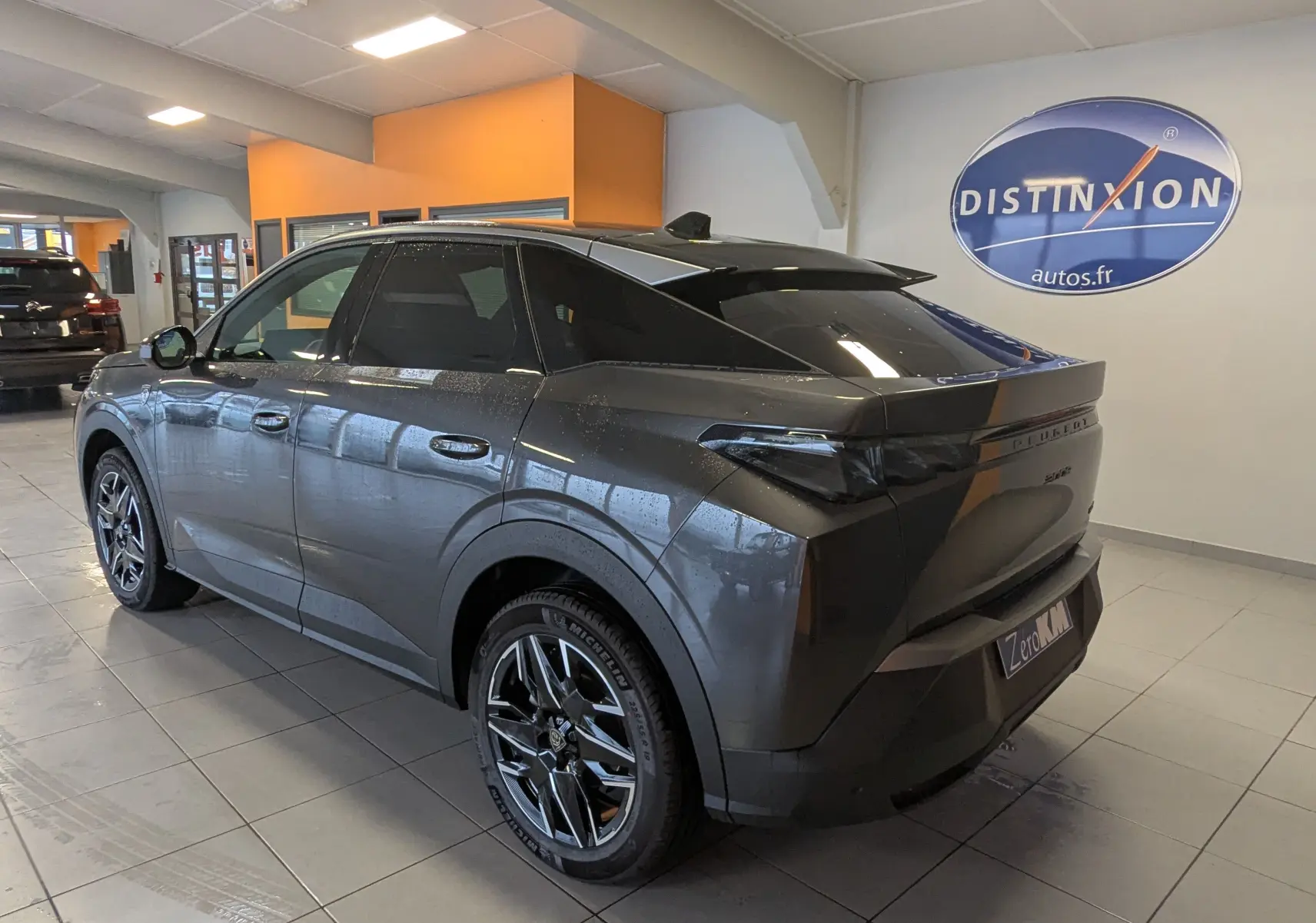 Peugeot 3008 Hybrid 145 GT gris titane toit noir, vue 3/4 arrière droit en intérieur avec jantes alliage 19 pouces.
