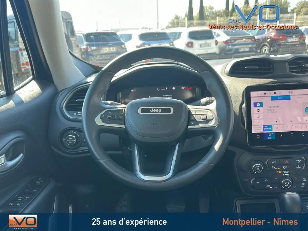 Vue intérieure centrée sur le volant Jeep noir et le tableau de bord avec écran tactile et commandes intégrées.