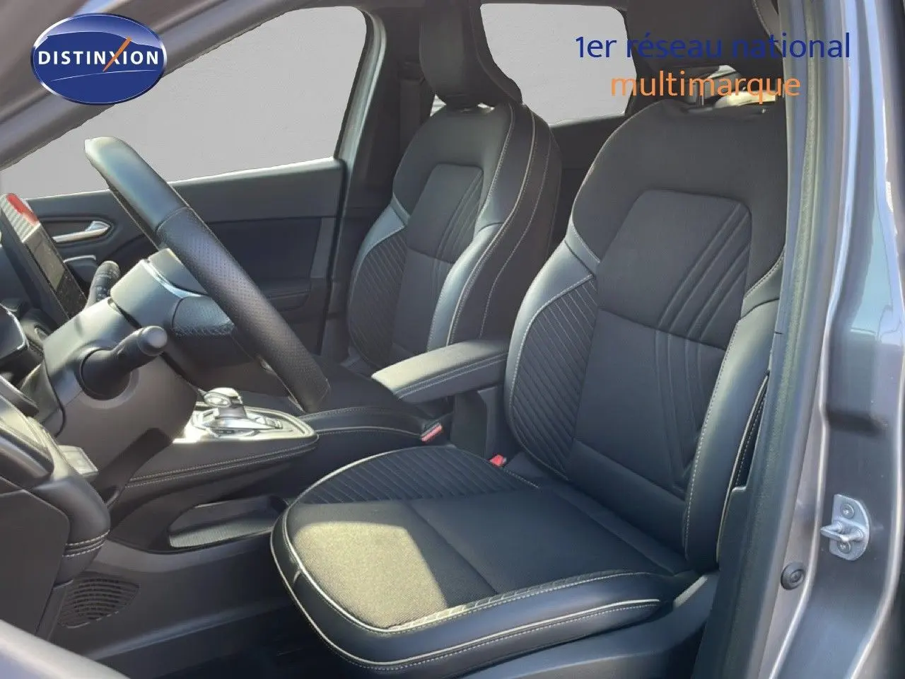 Vue intérieure côté conducteur du Renault Symbioz 2025 gris cassiopée, sièges noirs en tissu et cuir avec surpiqûres blanches.