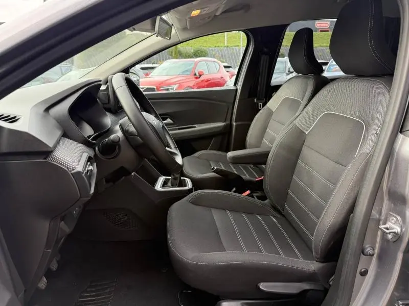 Vue intérieure côté conducteur du Dacia Jogger gris 2025, montrant les sièges avant et le volant avec boîte manuelle.