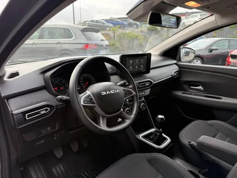 Vue intérieure côté conducteur du Dacia Jogger gris 2025, avec volant multifonction, écran tactile et boîte manuelle.