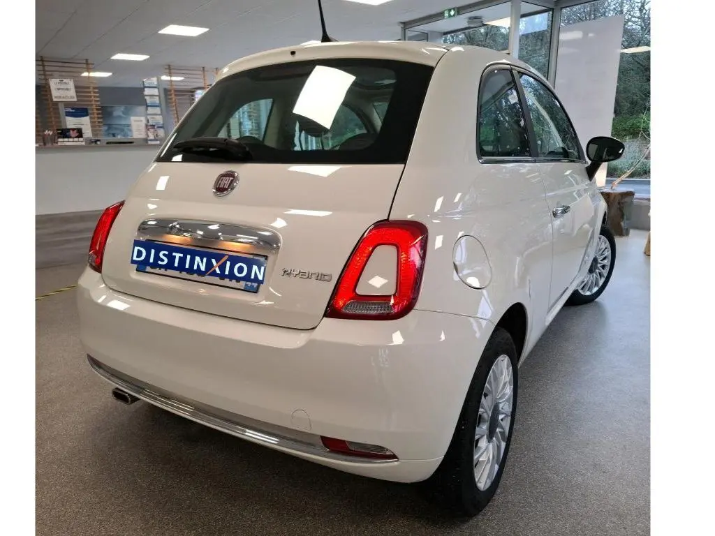 Vue 3/4 arrière droite de la FIAT 500 blanche Bossa Nova avec badge Hybrid, en intérieur showroom.