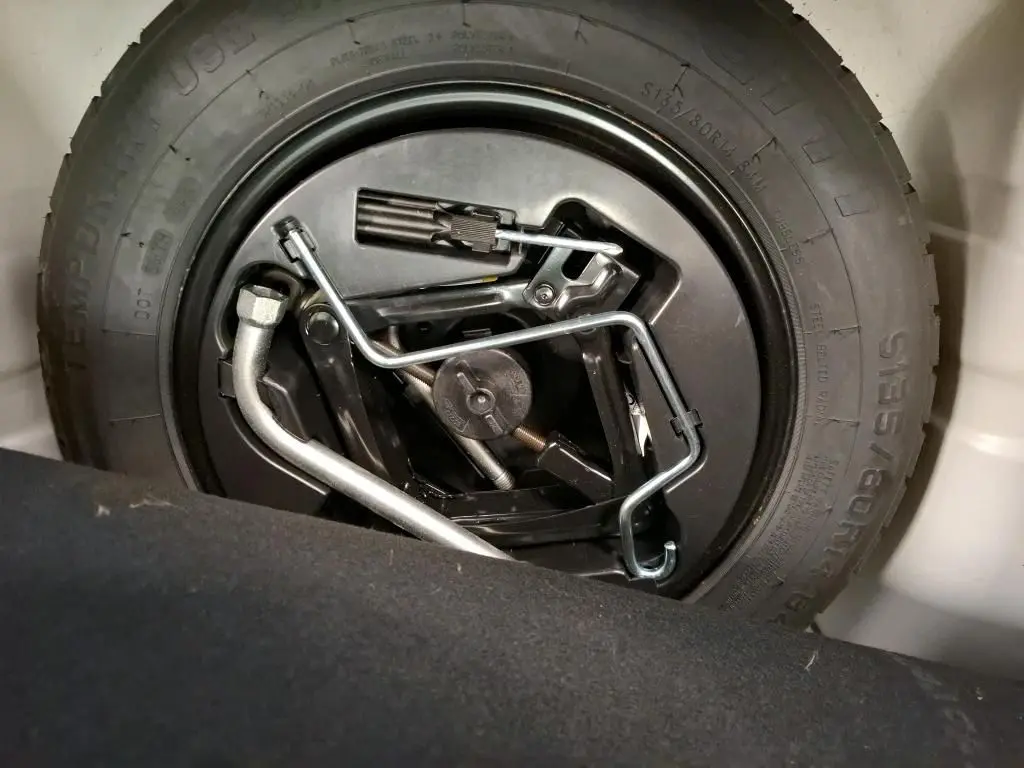 Gros plan sur la roue de secours et les outils de bord du coffre d'une FIAT 500 blanche, version Dolcevita 2022.