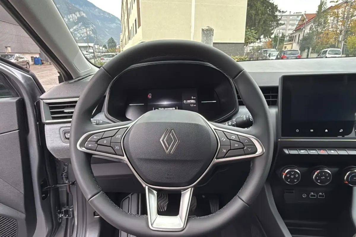 Vue intérieure centrée sur le volant cuir multifonctions de la Renault Clio gris rafale avec tableau de bord et écran tactile.