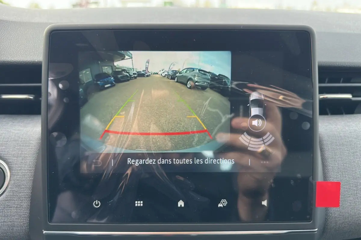 Écran tactile intérieur montrant la caméra de recul d'une Renault Clio gris rafale, avec vue arrière du parking.