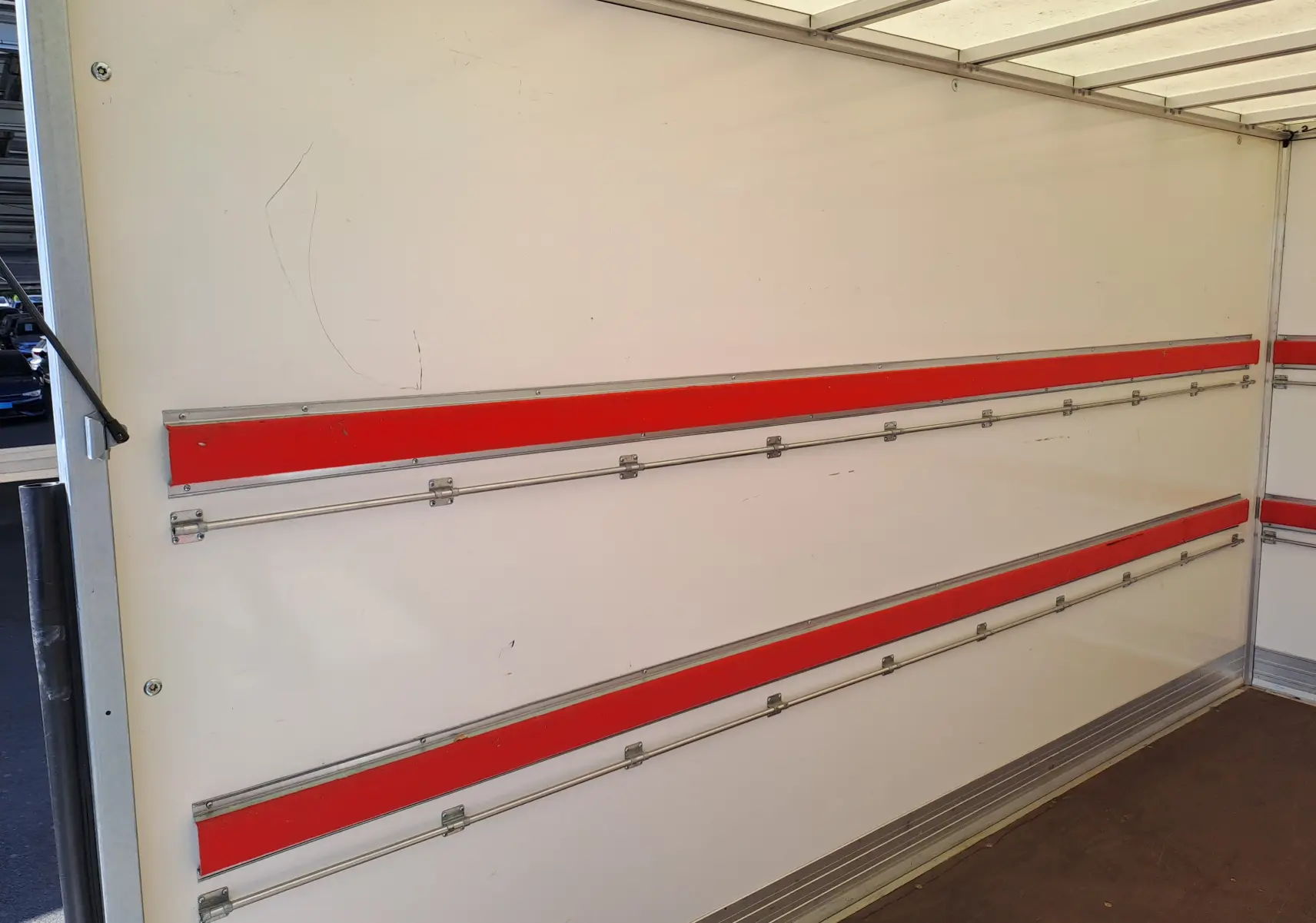 Vue intérieure du coffre blanc du Nissan Interstar Chassis Cabine L3H1 2024, avec rails métalliques et bandes rouges.