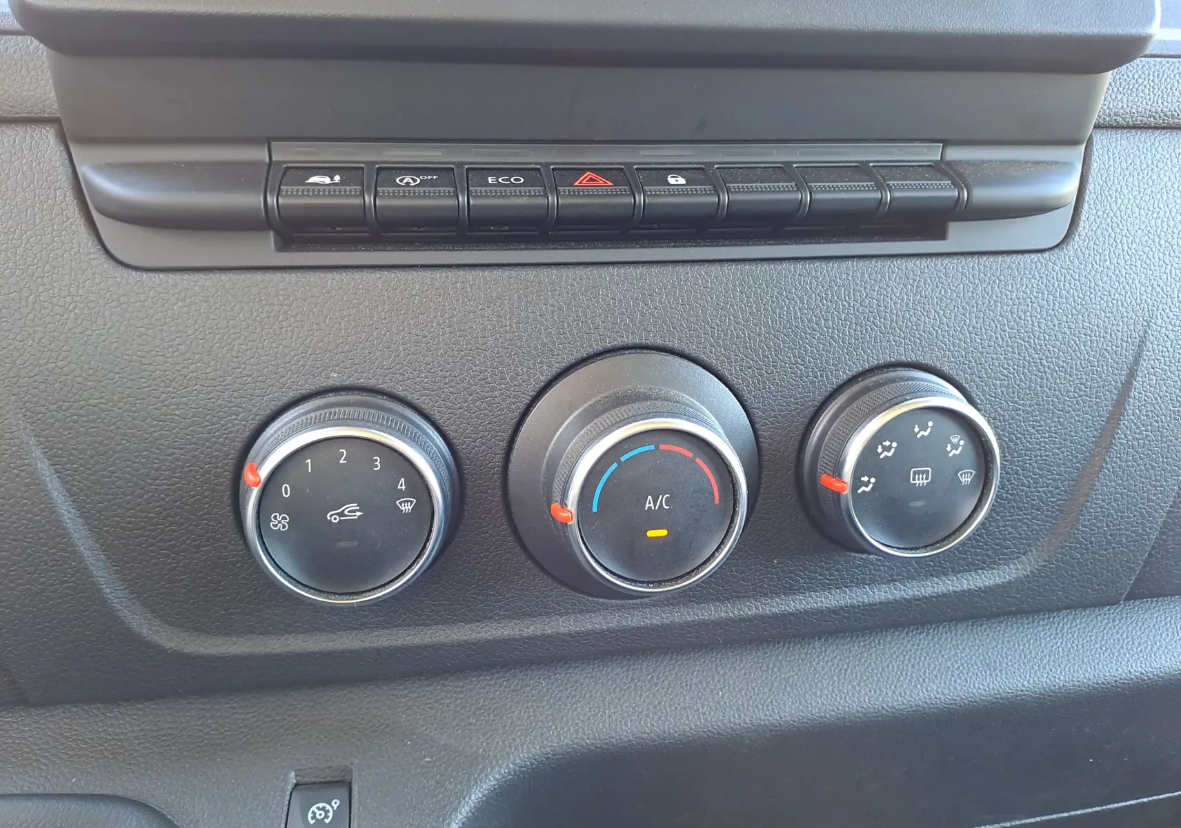 Gros plan sur les commandes de climatisation et boutons de fonction du tableau de bord du Nissan Interstar blanc 2024.