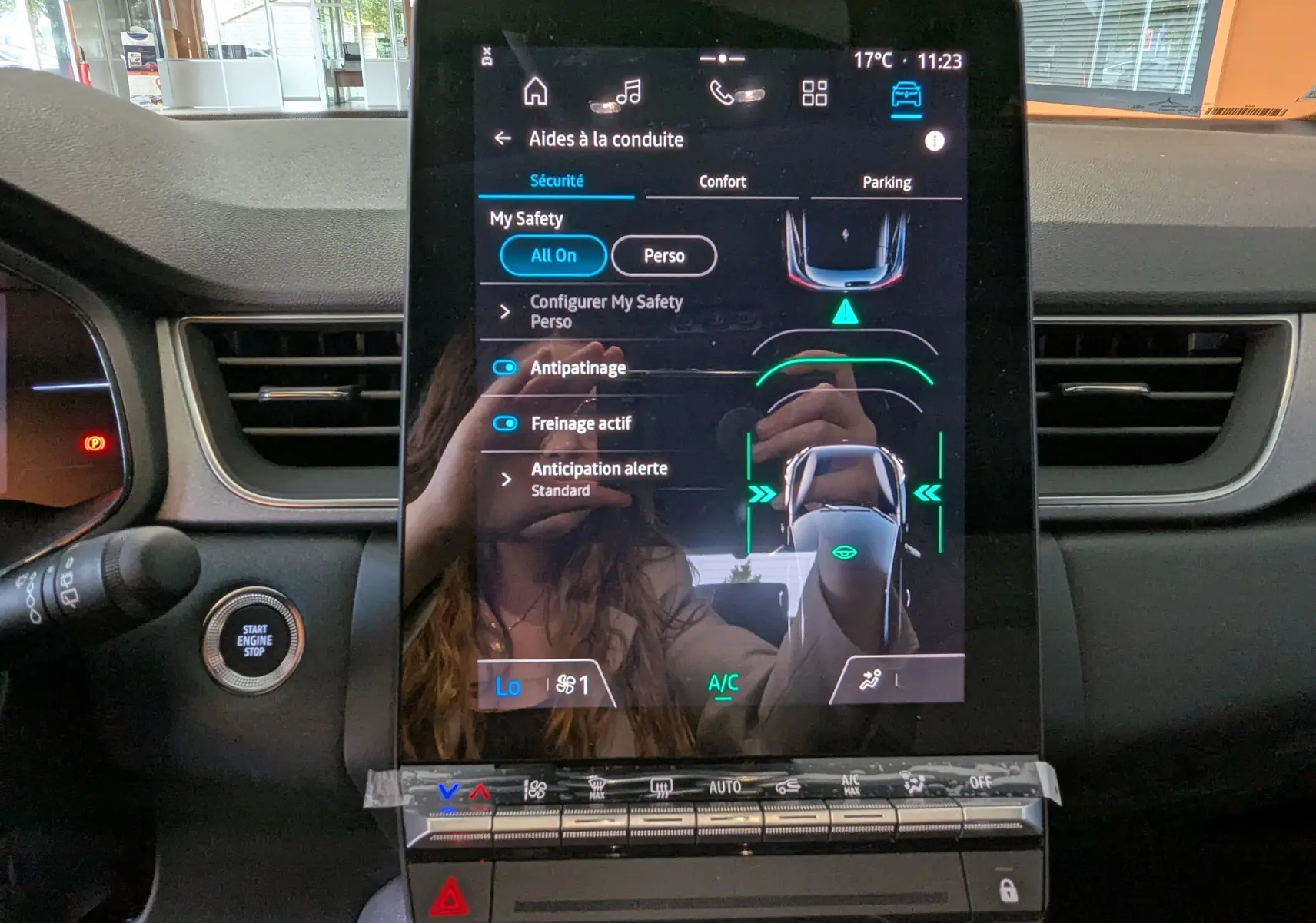 Écran tactile central du Renault Captur E-Tech 2025 affichant les aides à la conduite, avec tableau de bord noir et bouton start/stop.