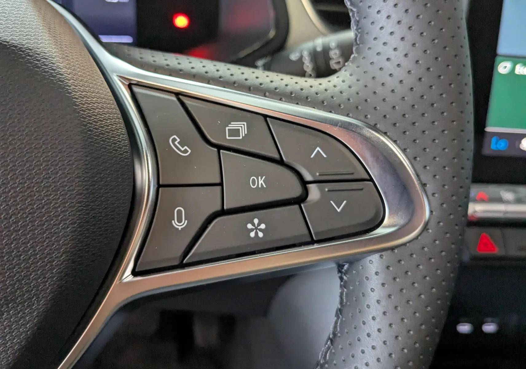 Gros plan sur les commandes multifonctions côté gauche du volant perforé du Renault Captur E-Tech blanc nacré 2025.