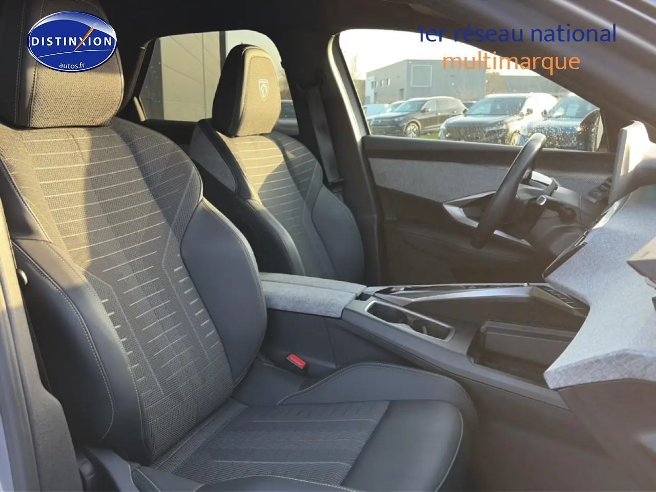 Vue intérieure côté conducteur du Peugeot 3008 gris 2025, mettant en valeur les sièges en tissu et cuir avec accoudoir central.