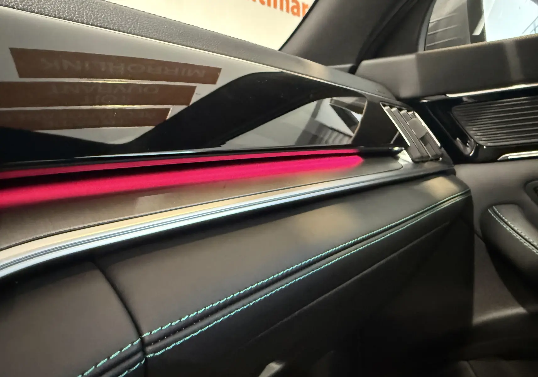 Détail intérieur du tableau de bord du BYD SEAL U 2026, avec éclairage d’ambiance rose et surpiqûres bleues sur cuir noir.