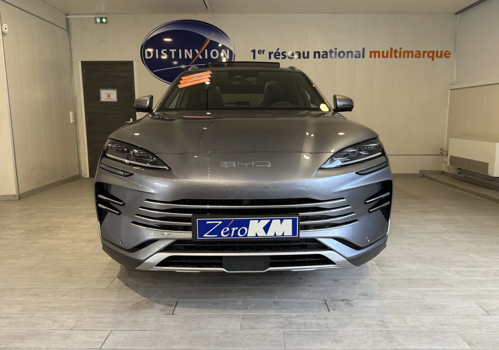 Vue frontale d'un BYD SEAL U 2026 gris métallisé avec calandre horizontale et phares LED fins en showroom.