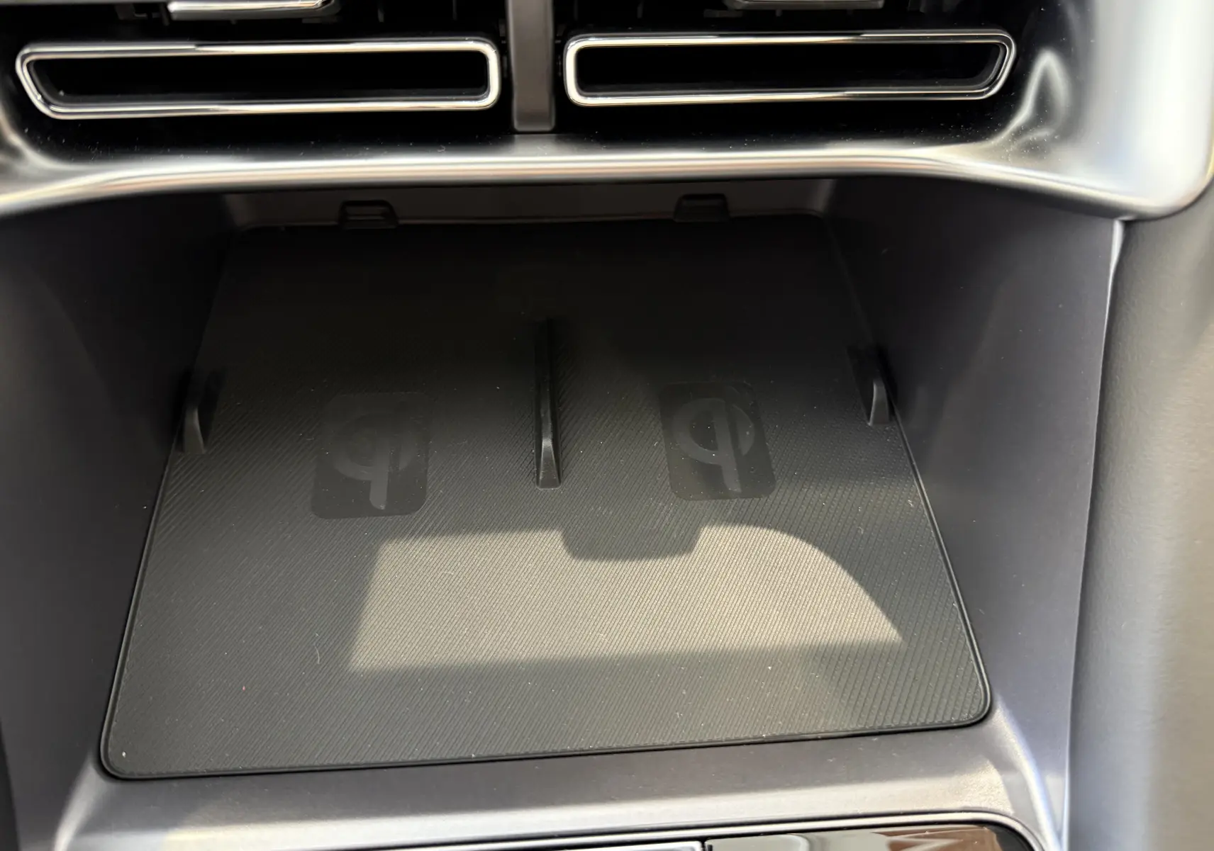 Gros plan sur le chargeur sans fil Qi intégré dans la console centrale du BYD SEAL U 2026, finition noire.