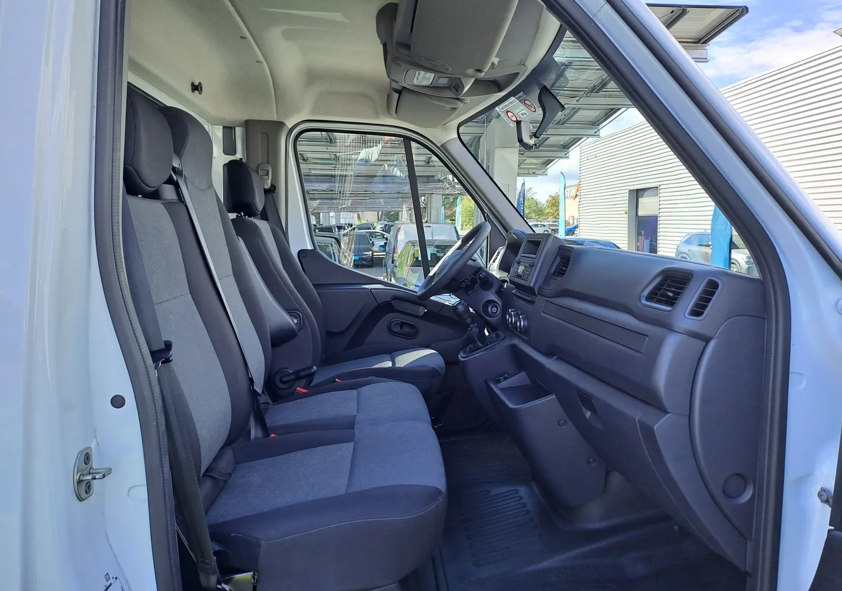 Vue intérieure côté conducteur du Nissan Interstar châssis cabine blanc 2024, montrant les sièges et le tableau de bord.